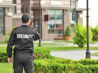 A uniformed security guard walking a patrol route around a building